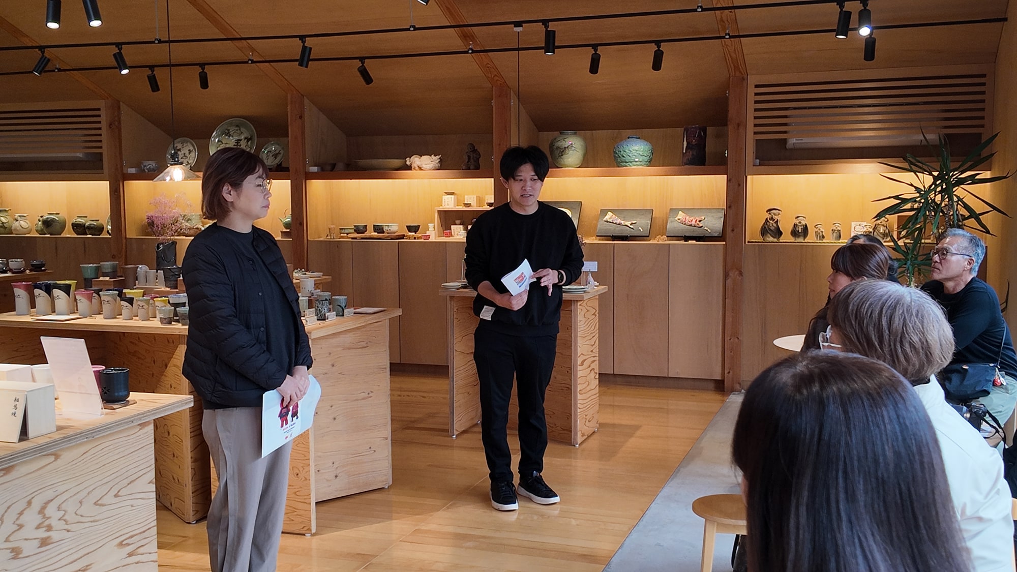 大堀相馬焼の器が並ぶ展示室で説明を聞く参加者